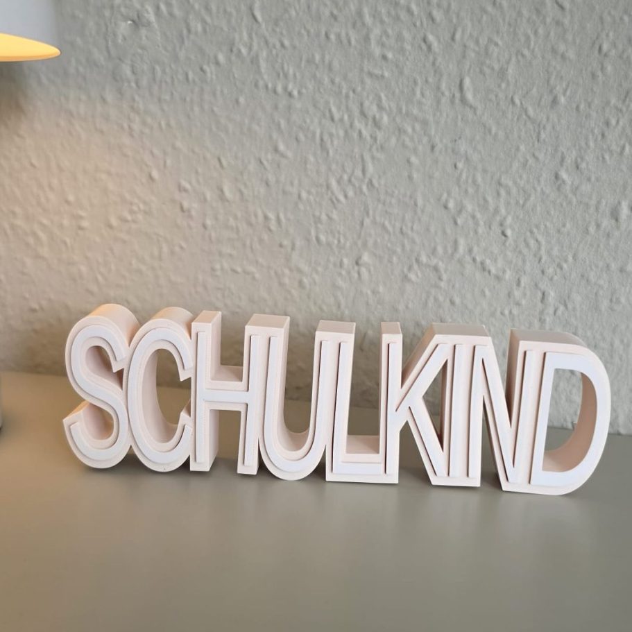 Dekorative Buchstaben bilden das Wort "SCHULKIND" auf einem Tisch.