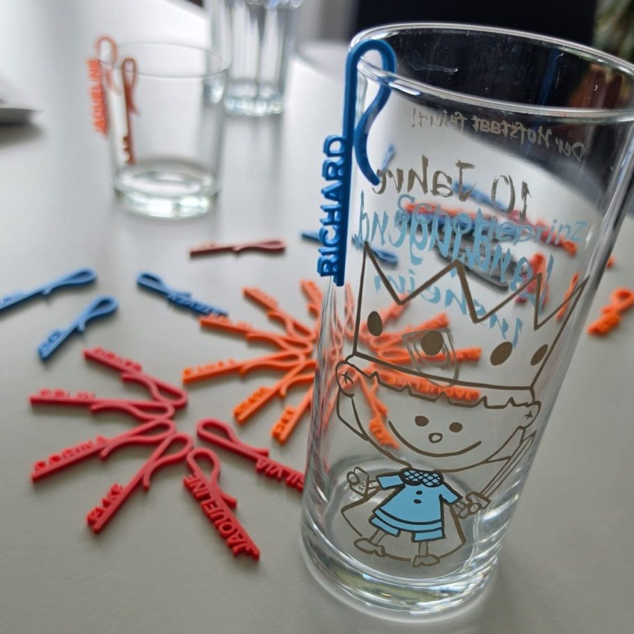 Ein Glas mit bunten Verzierungen und farbigen Figuren aus Kunststoff drumherum.